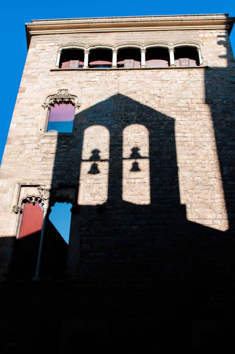 The shadow of this bell tower reflected perfectly on this bright sun filled wall.