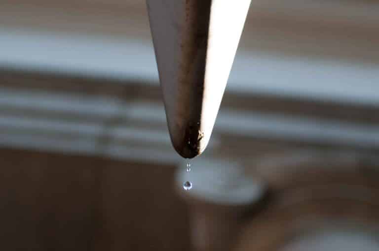 A single drop of water at the exact moment it falls from this gutter.