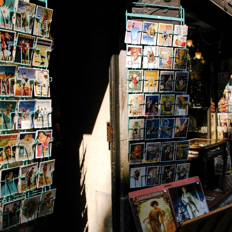 Colorful art nouveau postcards near a hidden side street in the Gothic Quarter.
