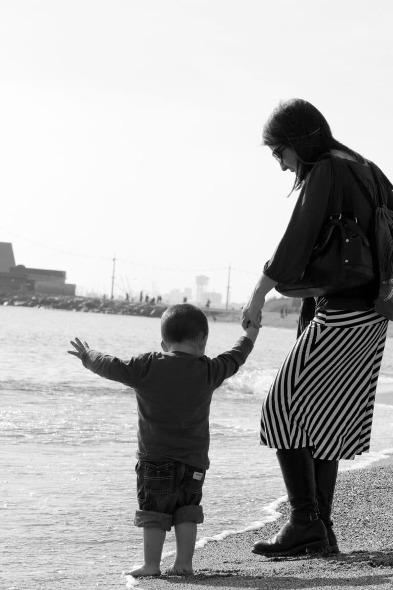 Mom holding her son´s hand as they walk along the shore on this Barcelona beach.