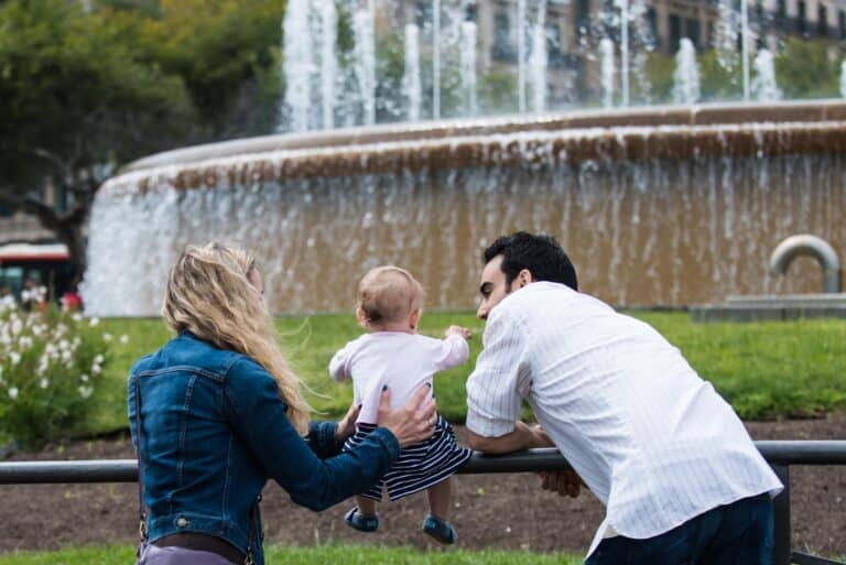 A family, mom, dad and their 1 year old in front of a fountain in Barcelona.
