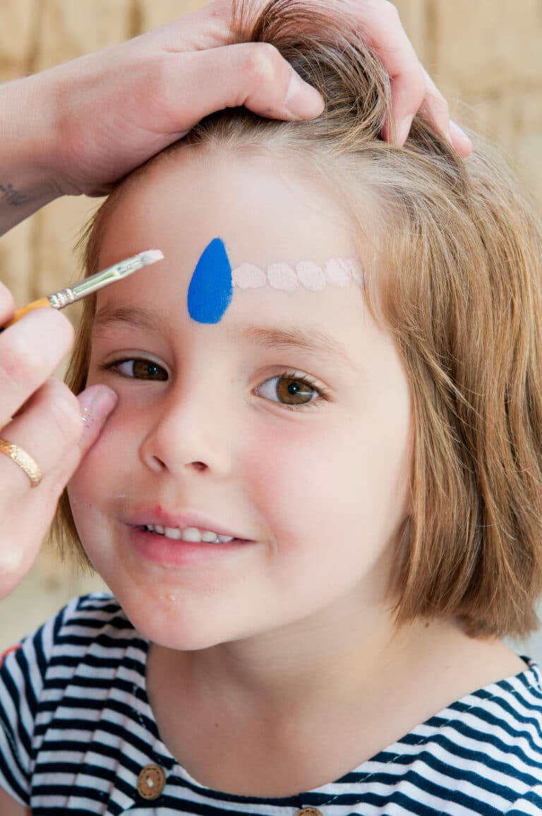 A 5 year old getting her face painted at this birthday party.