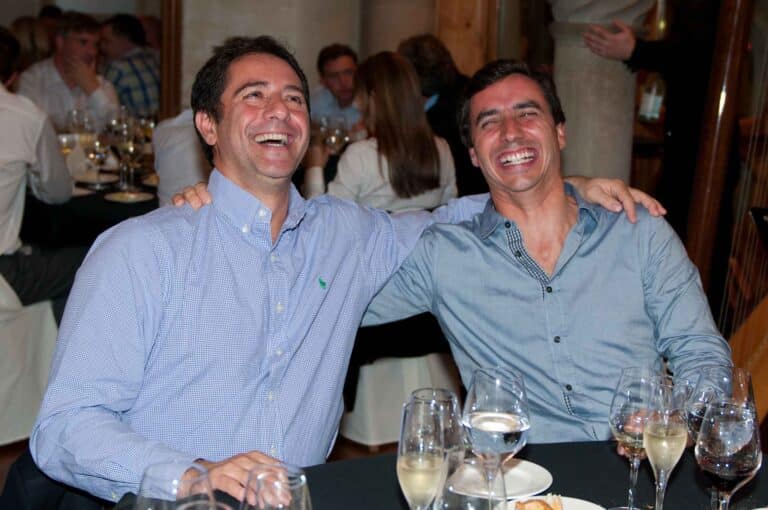 Two colleagues laughing during a group dinner.