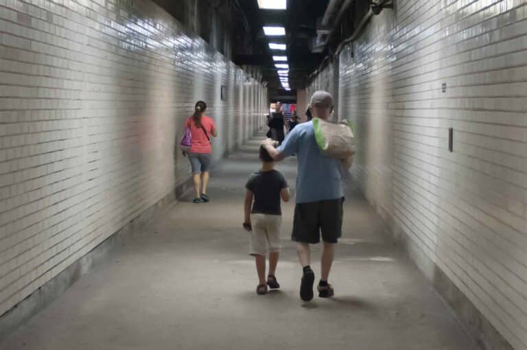A grandfather and his grandson walking in the metro.